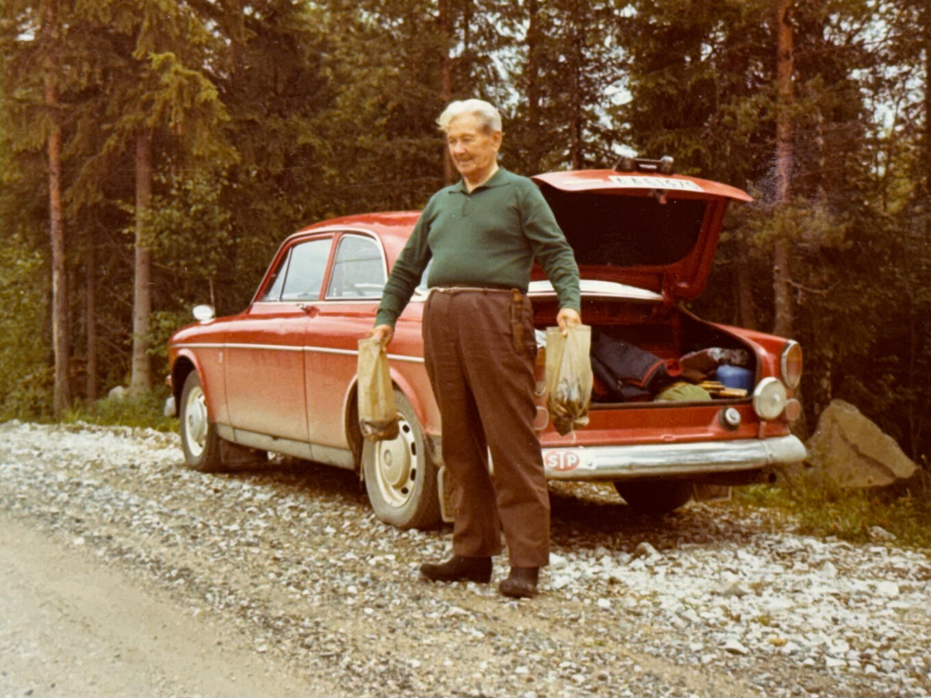 Great-grandfather after a fishing trip, standing beside a Volvo Amazon Sport.